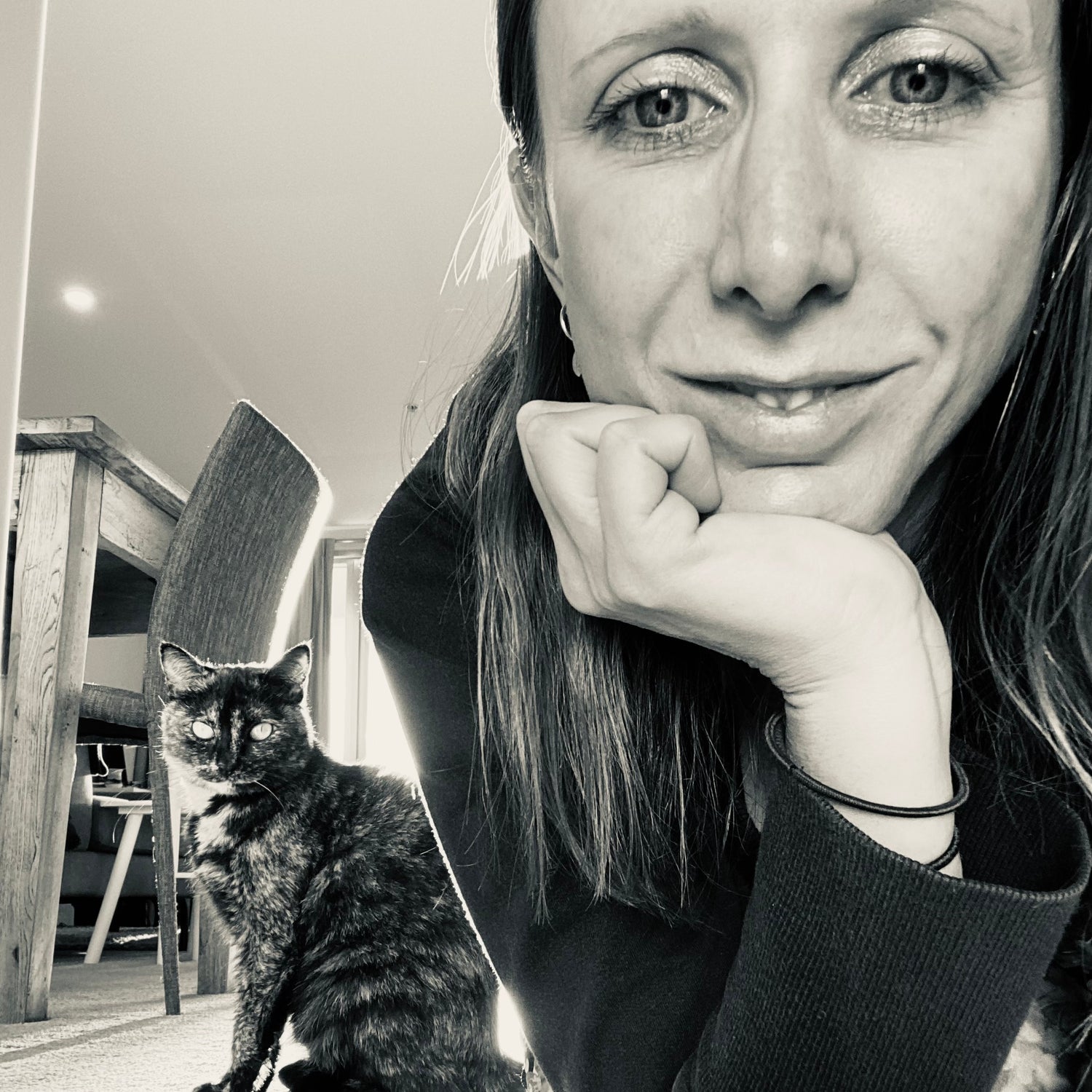 Deena Vallance (right) taking selfie with cat (left) on floor. Picture in black and white
